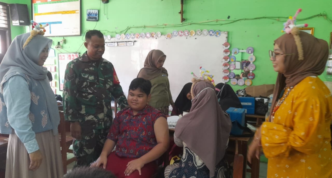 Perangi Campak dan Rubela, Babinsa Kebonbaru Dampingi Imunisasi Anak Sekolah